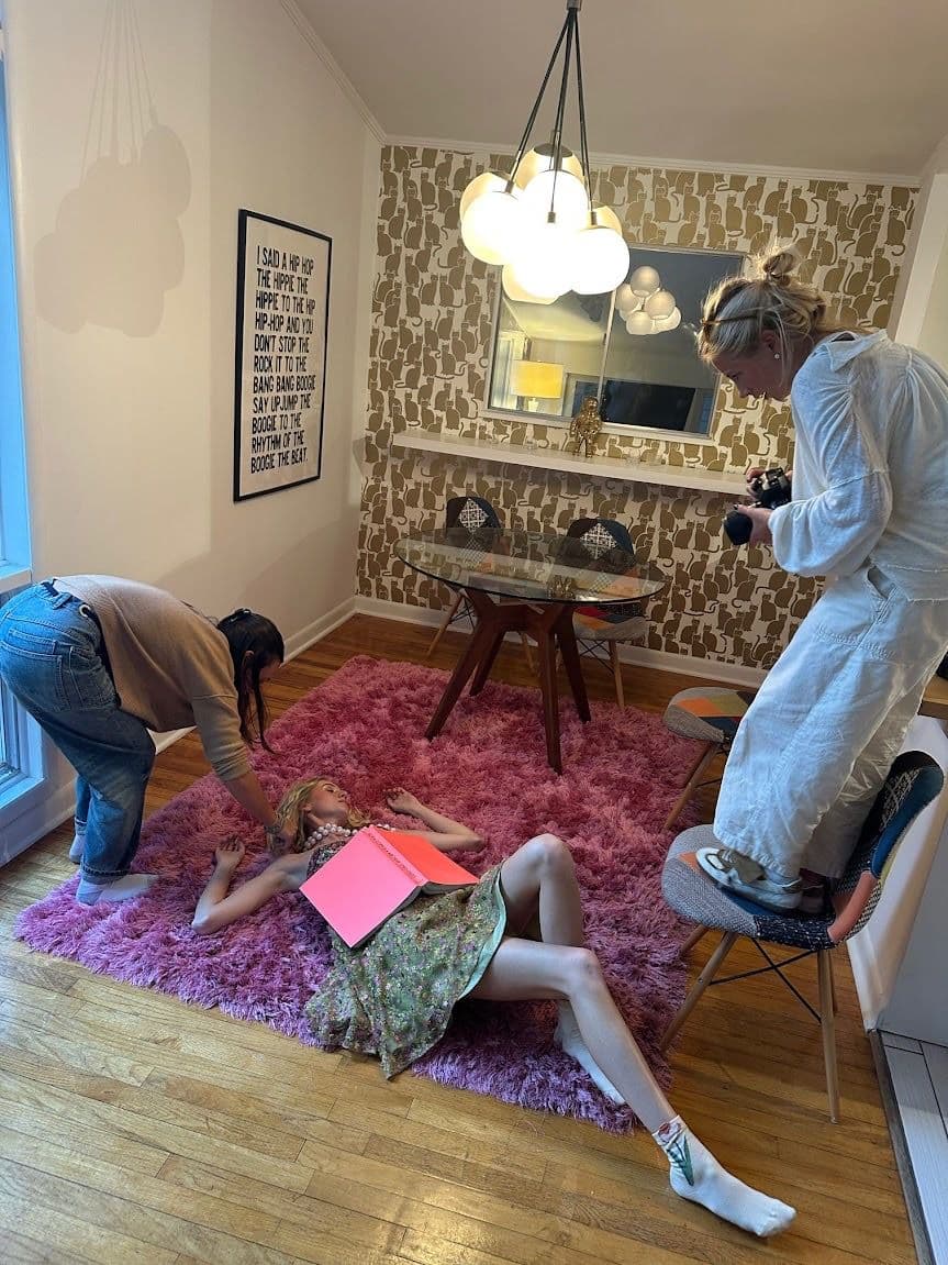 Crew styling a model on the pink rug under the bubble chandelier in the dining room