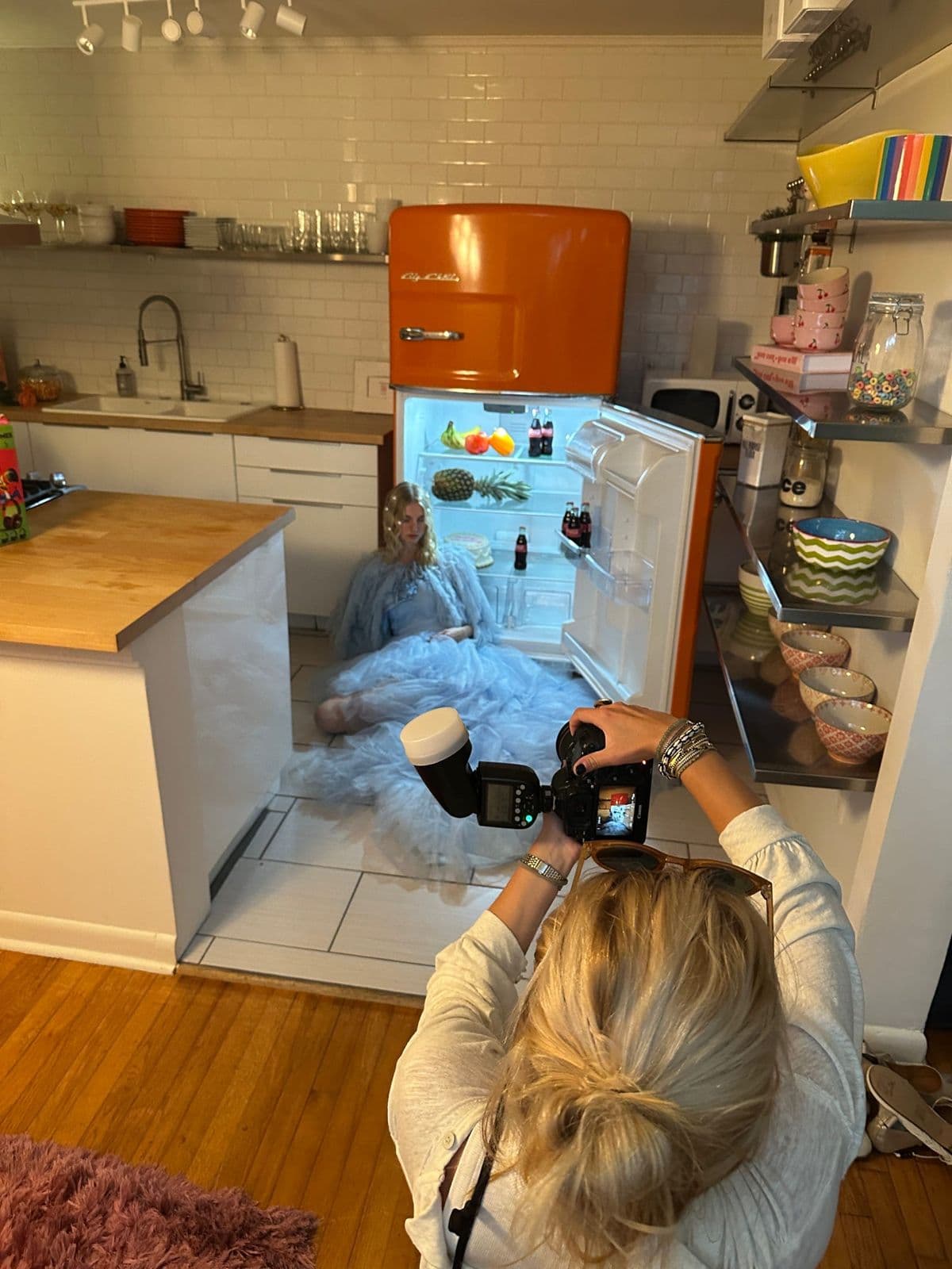 Photographer shooting a model through the open orange fridge door
