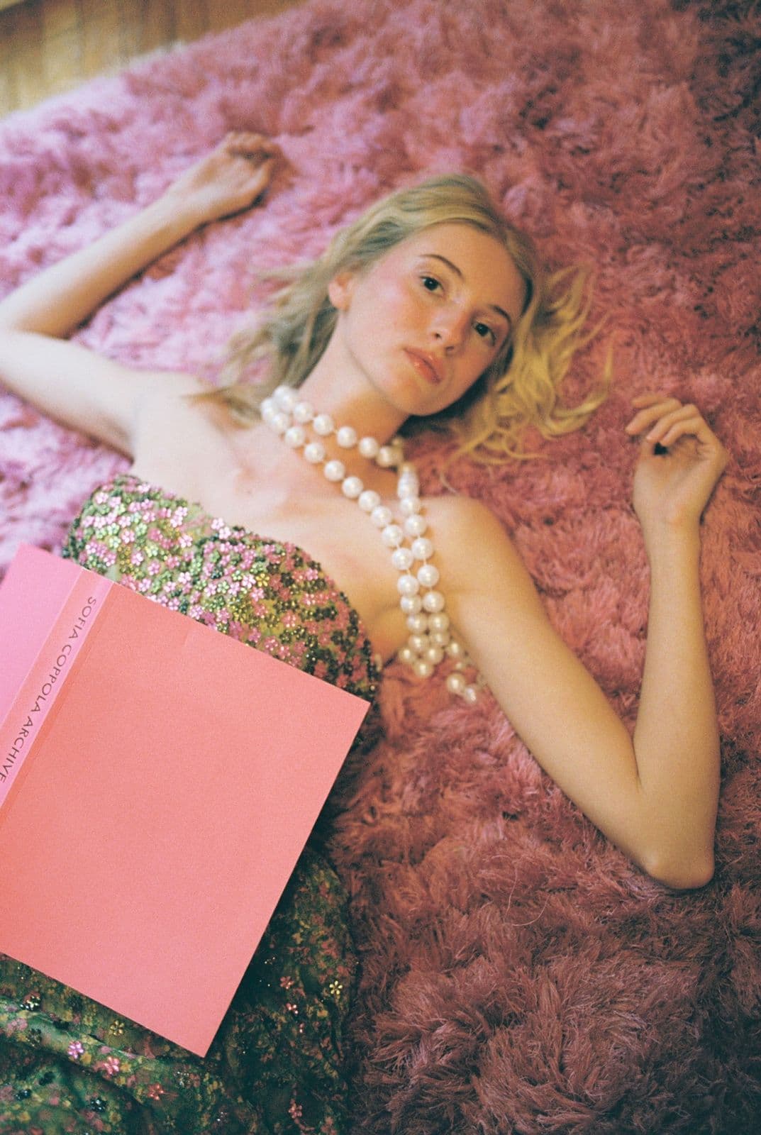 Portrait of a model with pearls lying on the pink shag rug